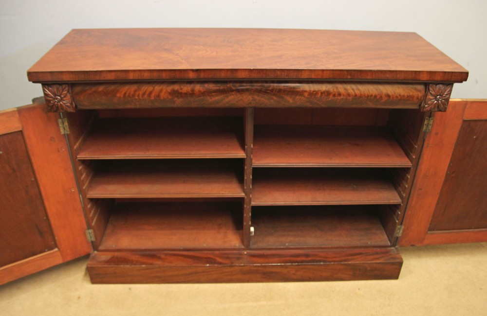 An antique Victorian flame mahogany chiffonier sideboard with two arched panel doors, carved corbels, and a plinth base. View X