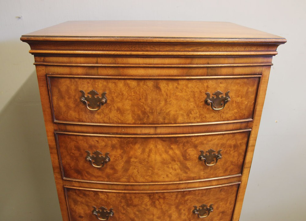 A tall burr walnut bow-front chest on chest featuring six stacked drawers, brass handles, and bracket feet. View VIII