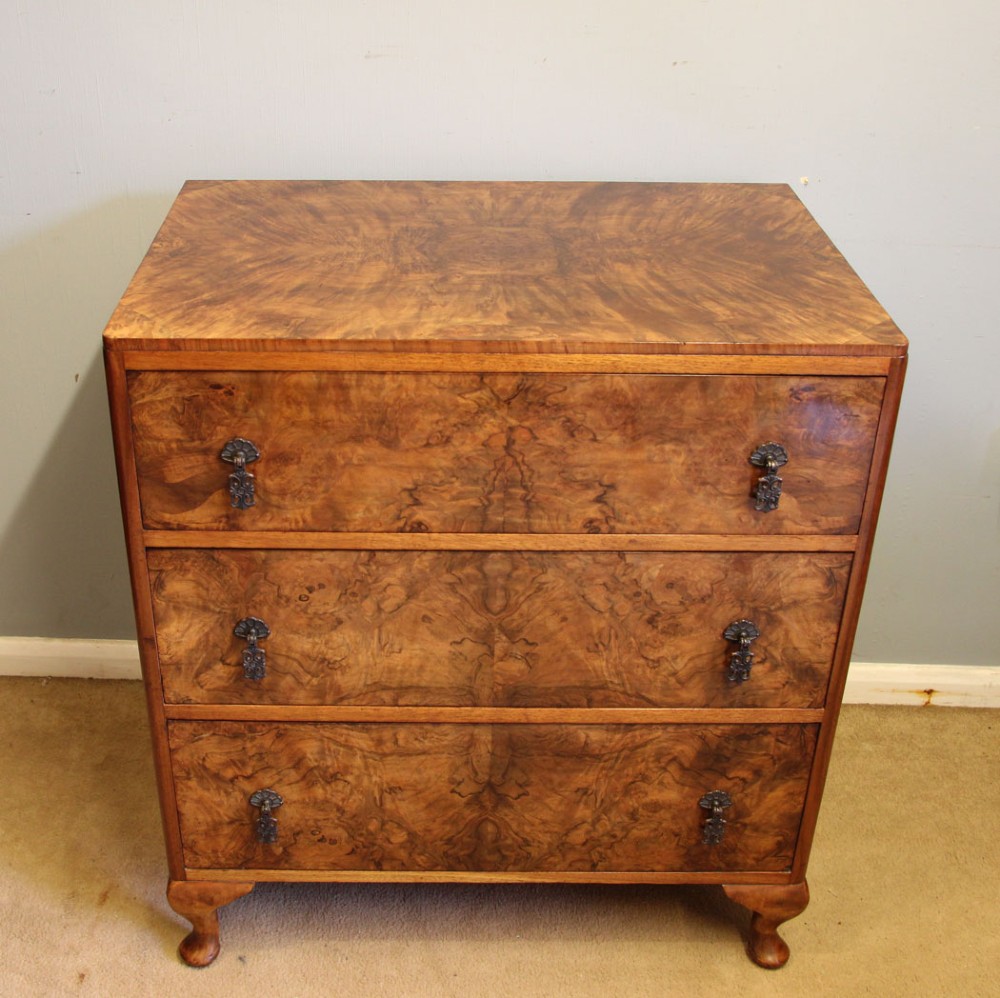 A three-drawer burr walnut chest of drawers featuring book-matched veneer patterns, ornate brass drop handles, and short cabriole legs. View II