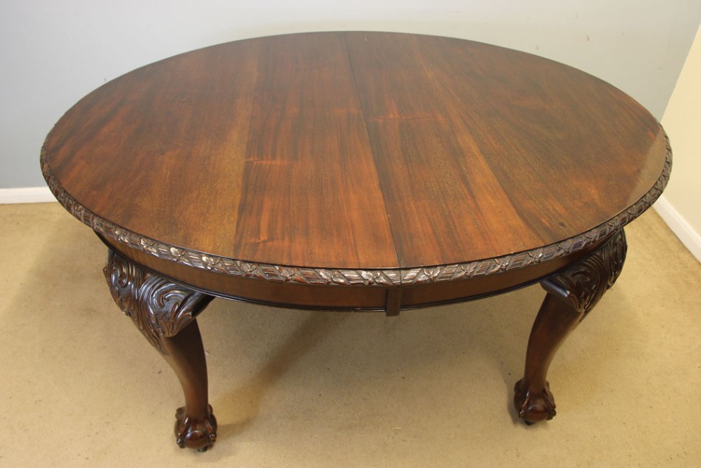 An oval mahogany extending dining table with two insert leaves, carved border edging, cabriole legs featuring acanthus knee carvings, and ball-and-claw feet. View II