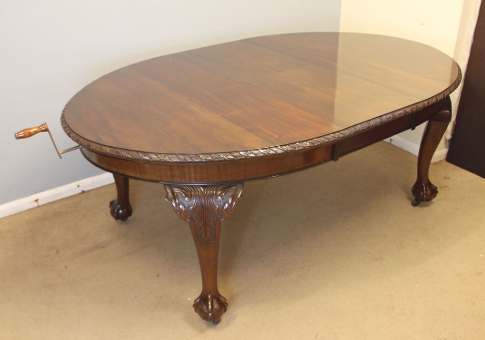 An oval mahogany extending dining table with two insert leaves, carved border edging, cabriole legs featuring acanthus knee carvings, and ball-and-claw feet. View VIII