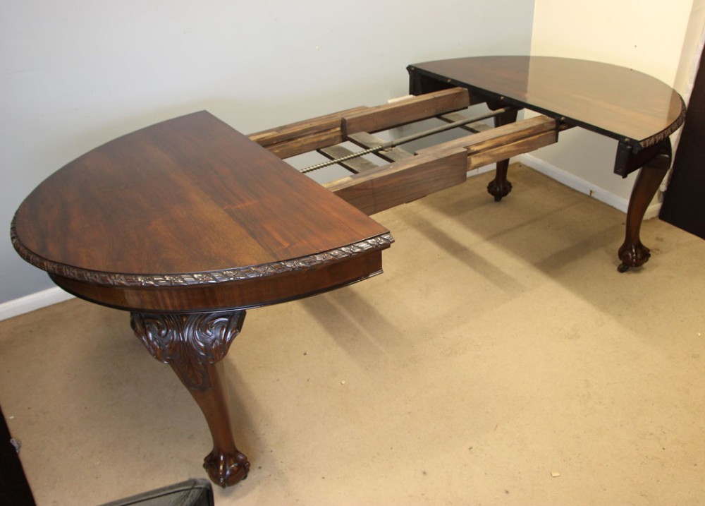 An oval mahogany extending dining table with two insert leaves, carved border edging, cabriole legs featuring acanthus knee carvings, and ball-and-claw feet. View XII