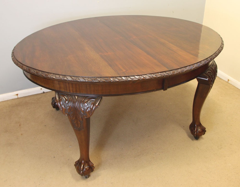 An oval mahogany extending dining table with two insert leaves, carved border edging, cabriole legs featuring acanthus knee carvings, and ball-and-claw feet. View XIII