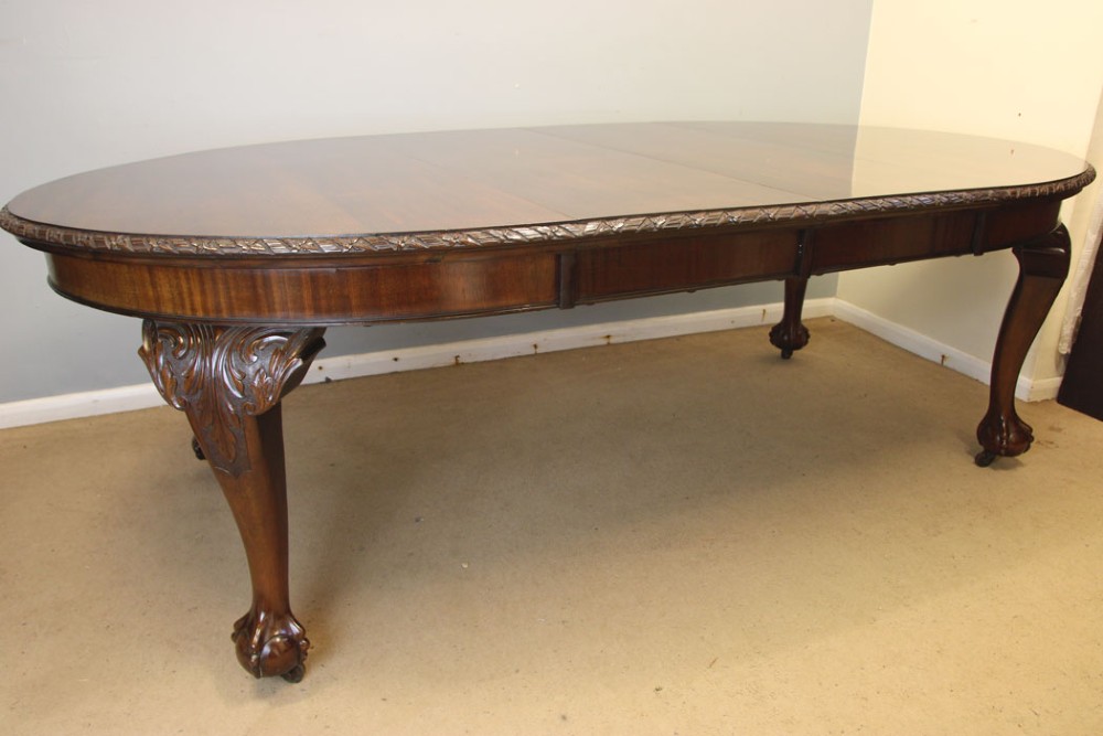 An oval mahogany extending dining table with two insert leaves, carved border edging, cabriole legs featuring acanthus knee carvings, and ball-and-claw feet. View XIV