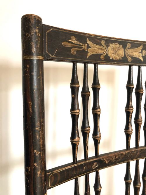 fig 1. An antique Regency period country rocking chair featuring a dark painted finish with gilt detailing, turned spindle back, shaped armrests, and a hand-woven rush seat.