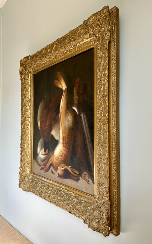 fig 2. A 19th-century game still life oil painting depicting a hung hare and pheasant inside an ornate gold gilt frame.