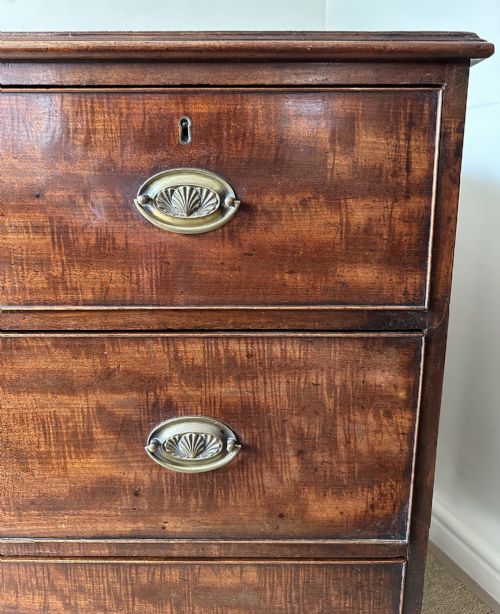 fig 1. An antique warm brown mahogany chest of drawers featuring two short drawers over two long drawers with brass oval handles and bracket feet.