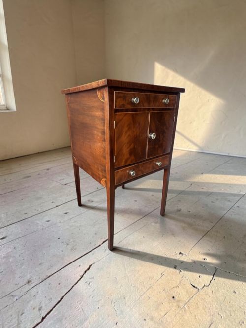fig 1. A Georgian flame mahogany bedside cabinet featuring a top drawer, central double doors, and a bottom drawer, supported by square tapered legs.