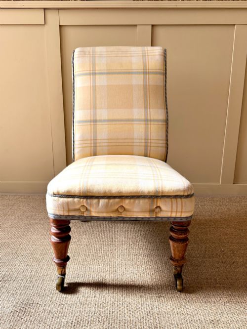 fig 1. A low-seated Victorian armless slipper chair upholstered in yellow and cream tartan fabric with turned mahogany front legs on brass castors.