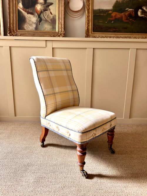 fig 2. A low-seated Victorian armless slipper chair upholstered in yellow and cream tartan fabric with turned mahogany front legs on brass castors.