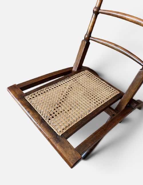 A nineteenth-century Aesthetic Movement folding campaign chair made from warm brown wood with a ladder back and woven cane seat. View III