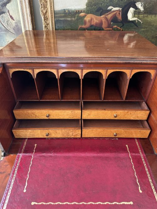 fig 2. An antique nineteenth-century mahogany Wellington secretaire chest with an open drop-front writing desk section revealing internal pigeonholes above three lower drawers.