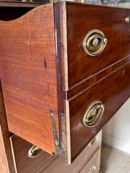fig 4. An antique nineteenth-century mahogany Wellington secretaire chest with an open drop-front writing desk section revealing internal pigeonholes above three lower drawers.