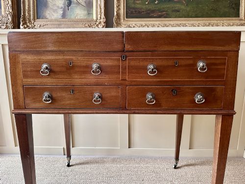 fig 1. A late Georgian mahogany gentlemans dressing table featuring two hinged side leaves open to reveal internal compartments and a central adjustable mirror, raised on square tapered legs with brass castors.