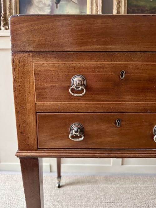 fig 2. A late Georgian mahogany gentlemans dressing table featuring two hinged side leaves open to reveal internal compartments and a central adjustable mirror, raised on square tapered legs with brass castors.