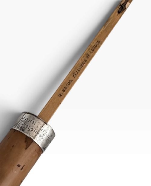 An antique malacca wood walking cane featuring a polished silver collar and cap. View IX
