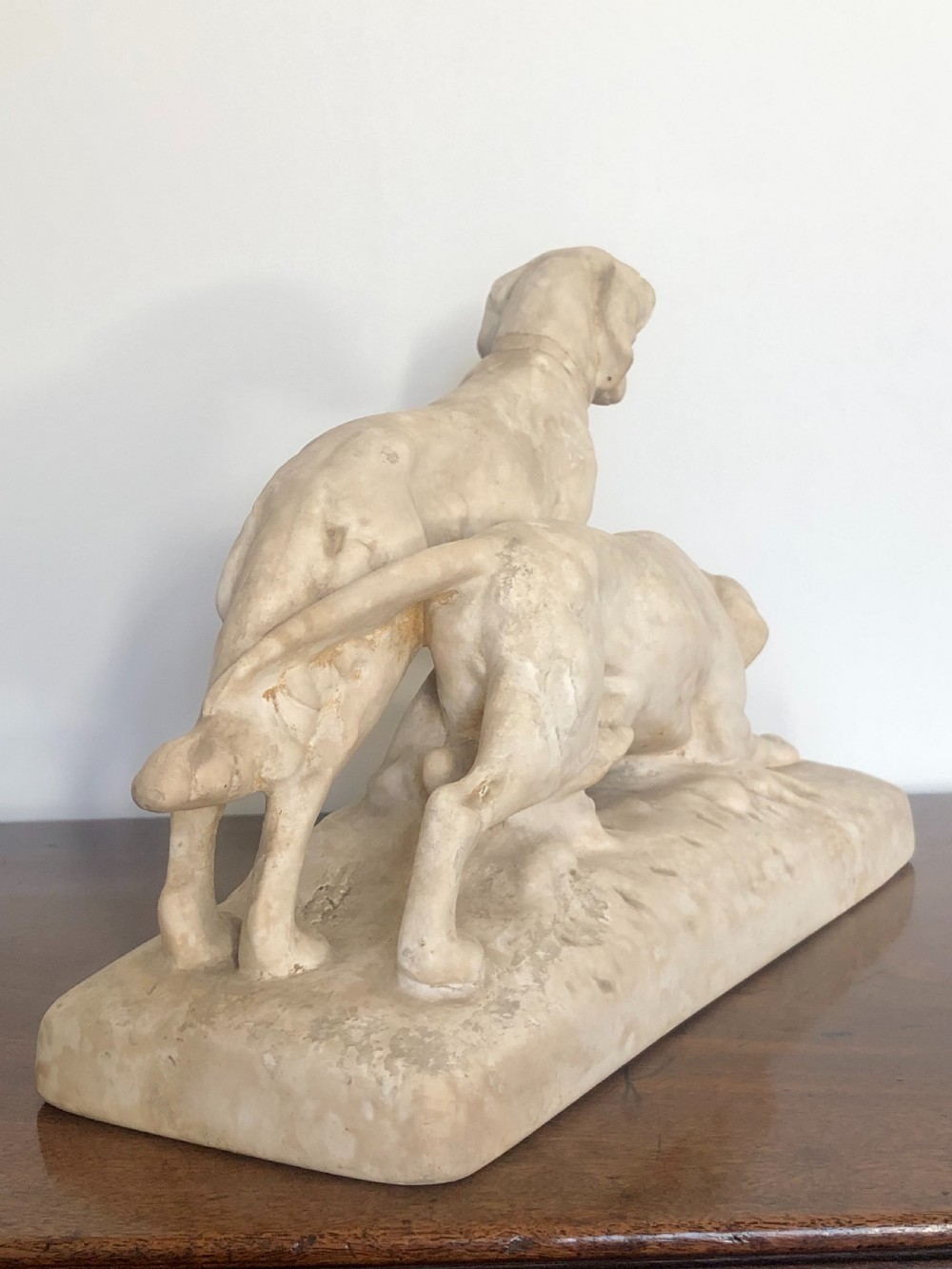 A 19th-century off-white Parian ware sculpture depicting two hunting hounds positioned on an integrated rectangular base. View V