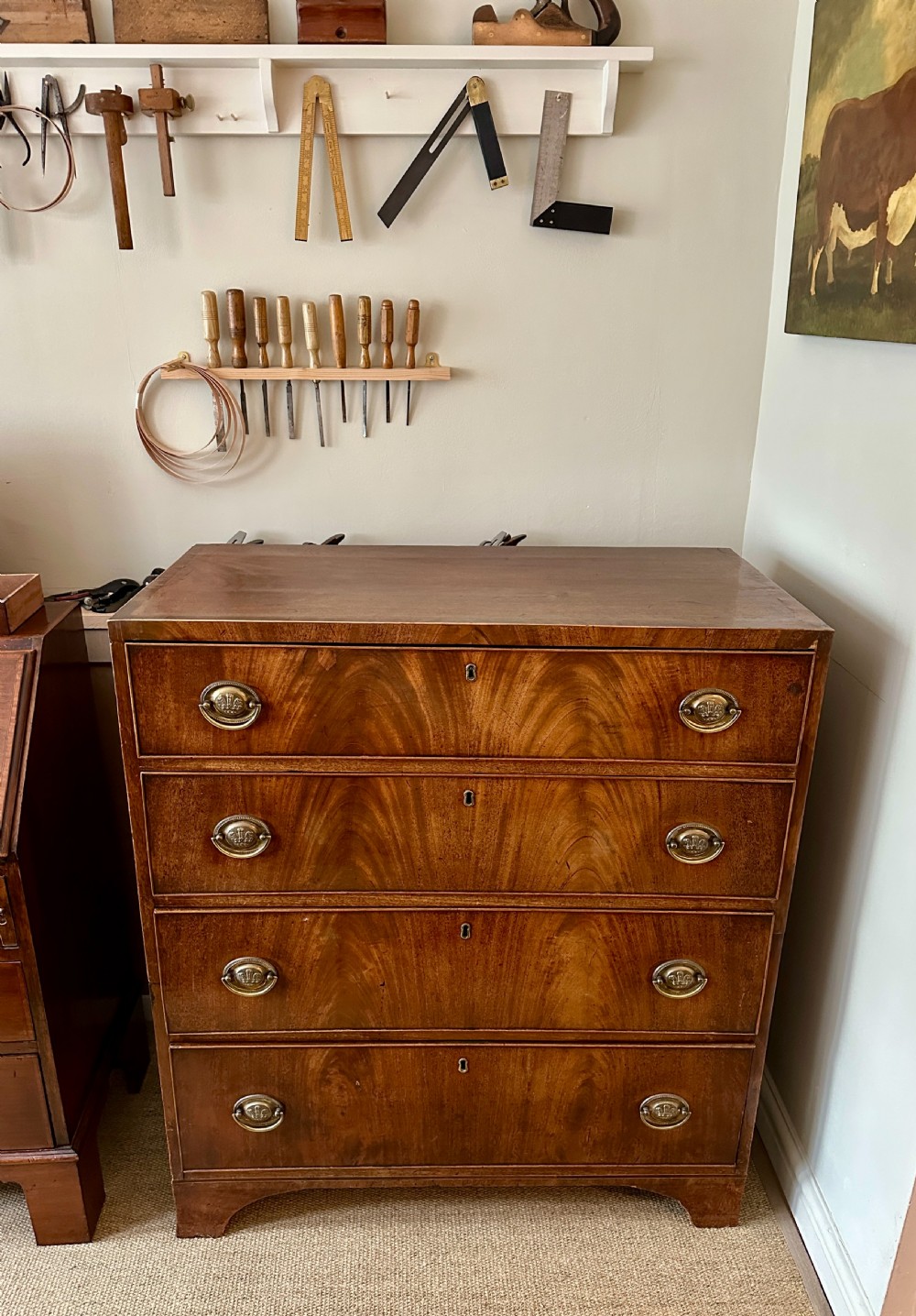A Georgian flame mahogany two-part chest of drawers featuring four long drawers with brass oval handles and keyhole escutcheons.
