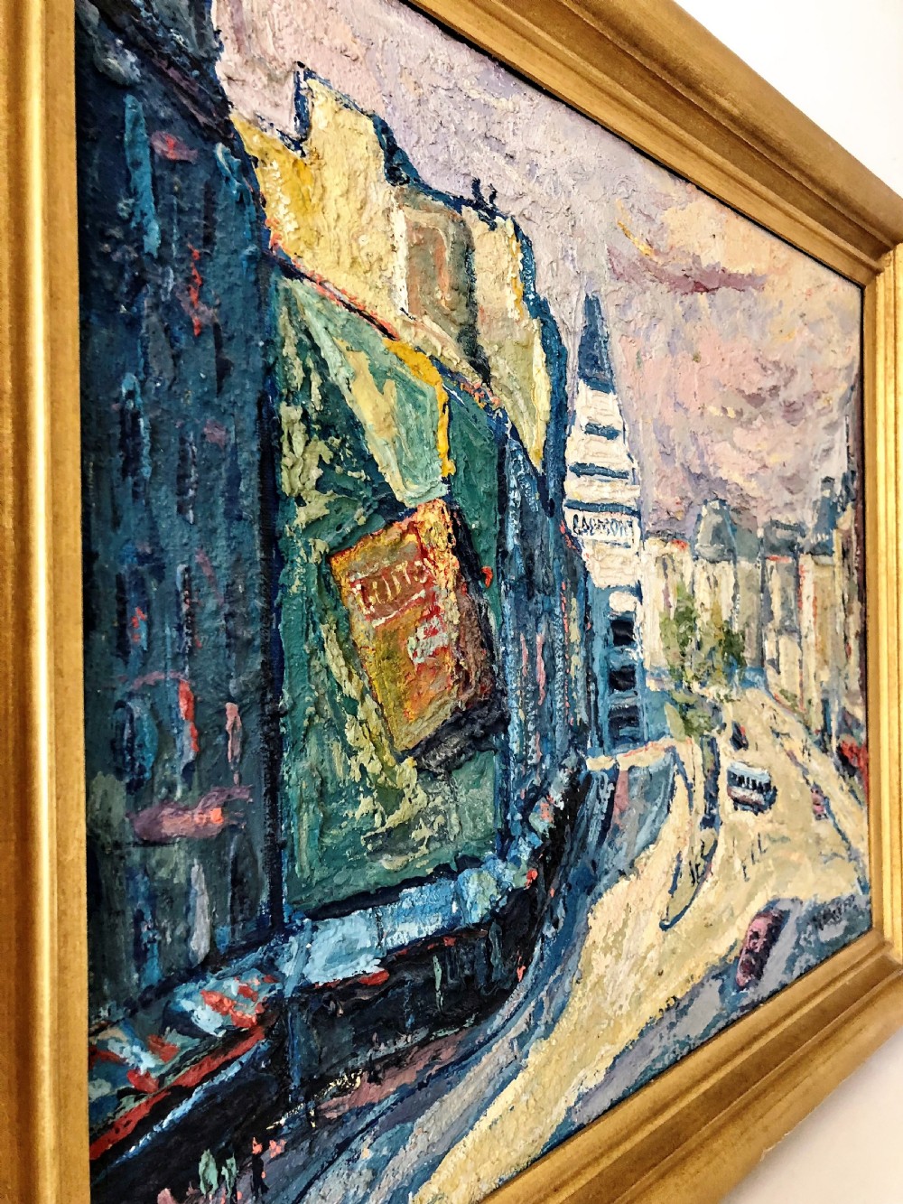 A framed mid-century oil painting depicting a Paris street scene rendered in heavy impasto strokes with yellow, blue, and pink tones inside a molded gold frame. View III