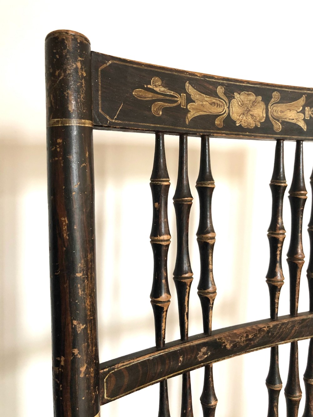 An antique Regency period country rocking chair featuring a dark painted finish with gilt detailing, turned spindle back, shaped armrests, and a hand-woven rush seat. View II