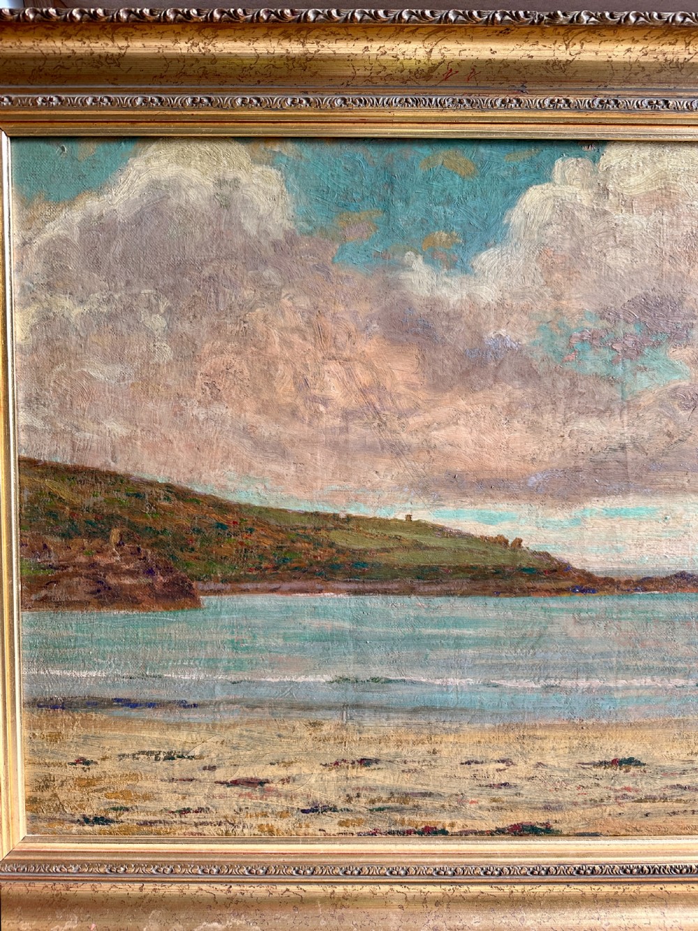 An early 20th-century framed oil painting depicting Porthmeor Beach with sandy shores and headland under a cloudy sky in a decorative gold frame. View III