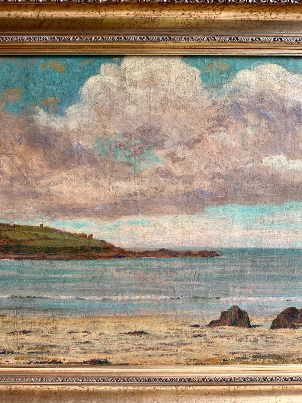 An early 20th-century framed oil painting depicting Porthmeor Beach with sandy shores and headland under a cloudy sky in a decorative gold frame. View IV