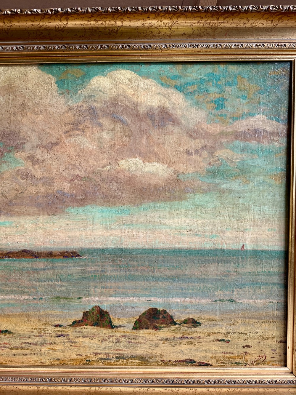 An early 20th-century framed oil painting depicting Porthmeor Beach with sandy shores and headland under a cloudy sky in a decorative gold frame. View V