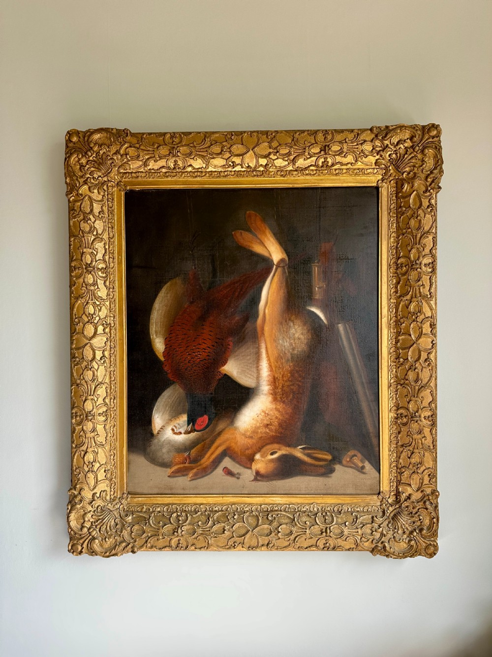 A 19th-century game still life oil painting depicting a hung hare and pheasant inside an ornate gold gilt frame.