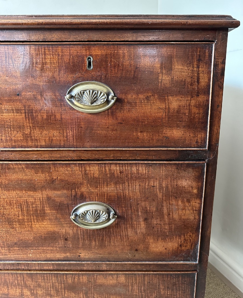 An antique warm brown mahogany chest of drawers featuring two short drawers over two long drawers with brass oval handles and bracket feet. View II