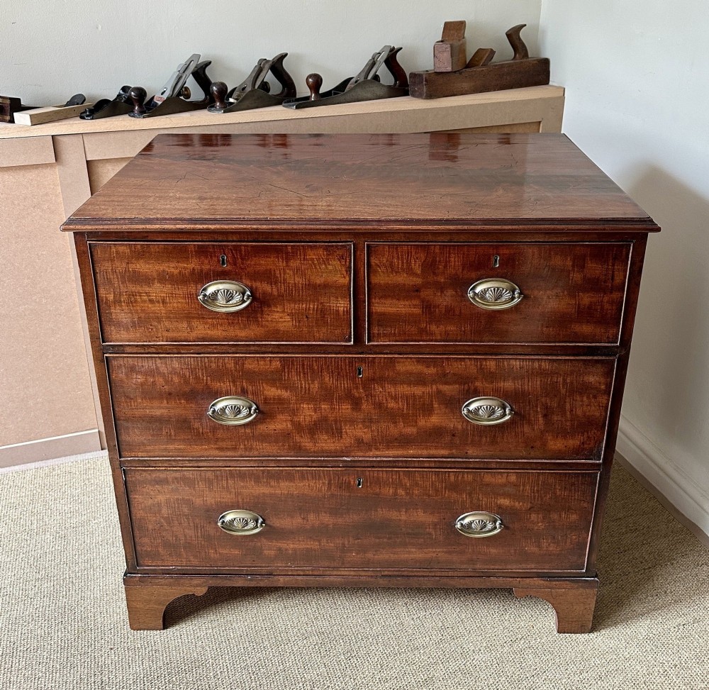 An antique warm brown mahogany chest of drawers featuring two short drawers over two long drawers with brass oval handles and bracket feet. View III