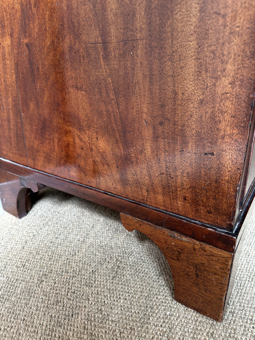 An antique warm brown mahogany chest of drawers featuring two short drawers over two long drawers with brass oval handles and bracket feet. View VI