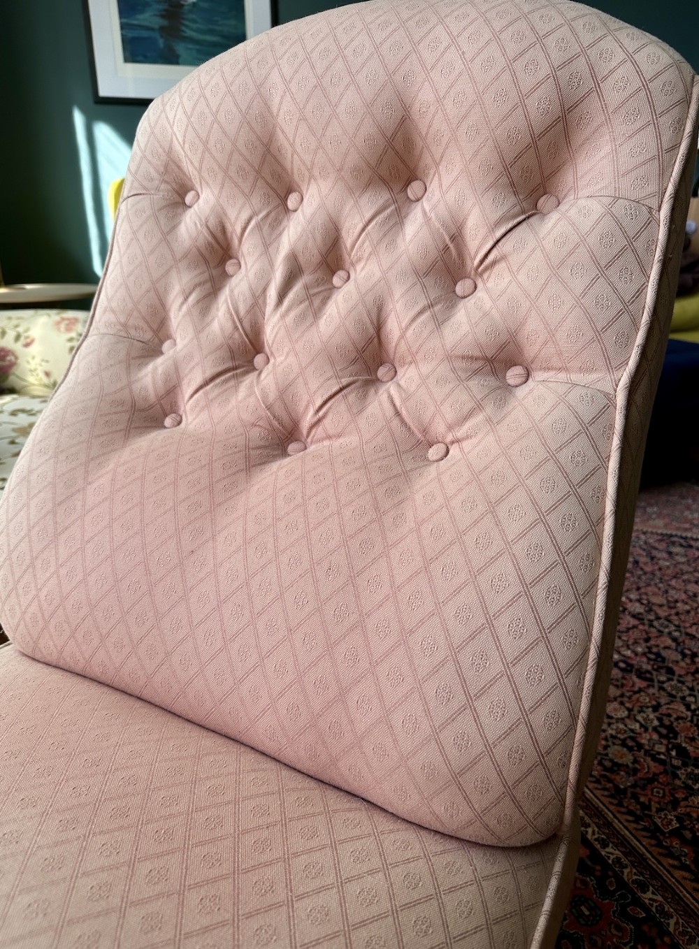 A low-seated Victorian slipper chair upholstered in dusty pink patterned fabric featuring a button-back design and turned dark timber legs with brass castors. View IV