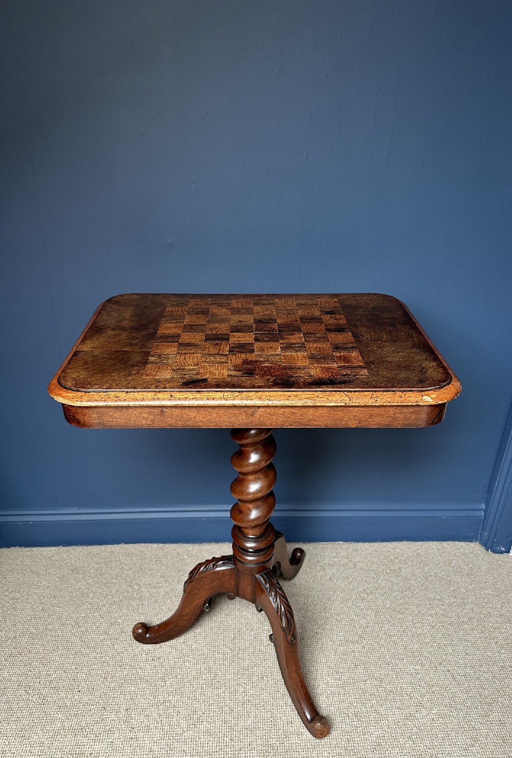 A Victorian walnut games table featuring a square top with an inlaid wooden chessboard surface, supported by a central barley twist column and carved tripod legs.