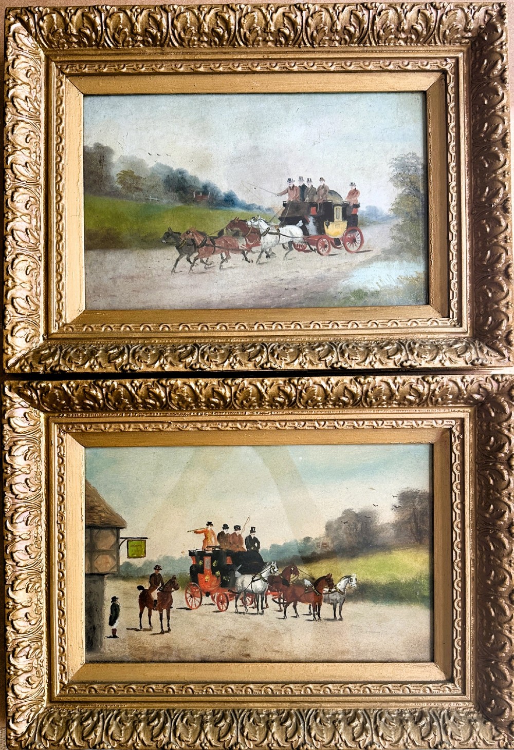 A pair of framed Edwardian oil paintings depicting horse-drawn mail coaches traveling through rural English landscapes.