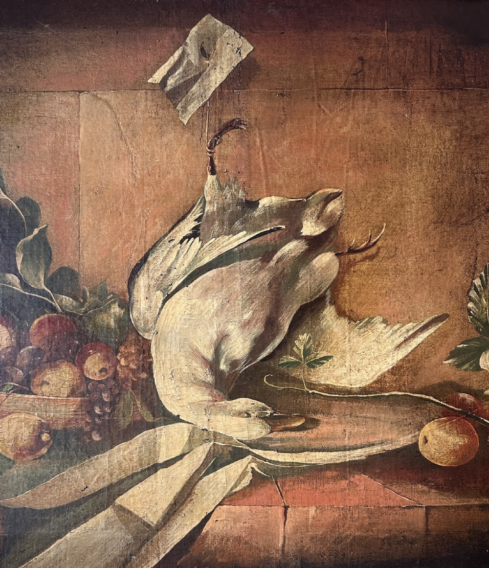 A 19th-century Continental school oil painting depicting hanging game birds and fruit arranged on a stone ledge within a gilded frame. View VII