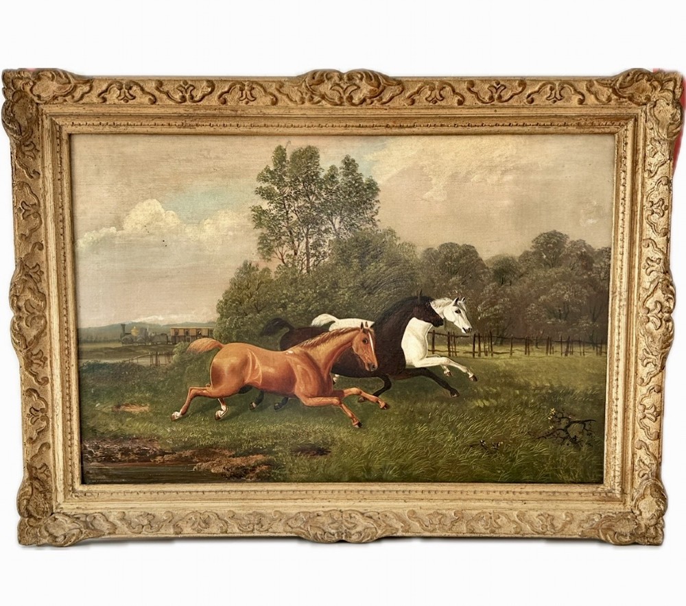 A 19th-century oil painting on canvas depicting three galloping horses in a landscape with a steam train in the background, framed in an ornate gilded wood frame.