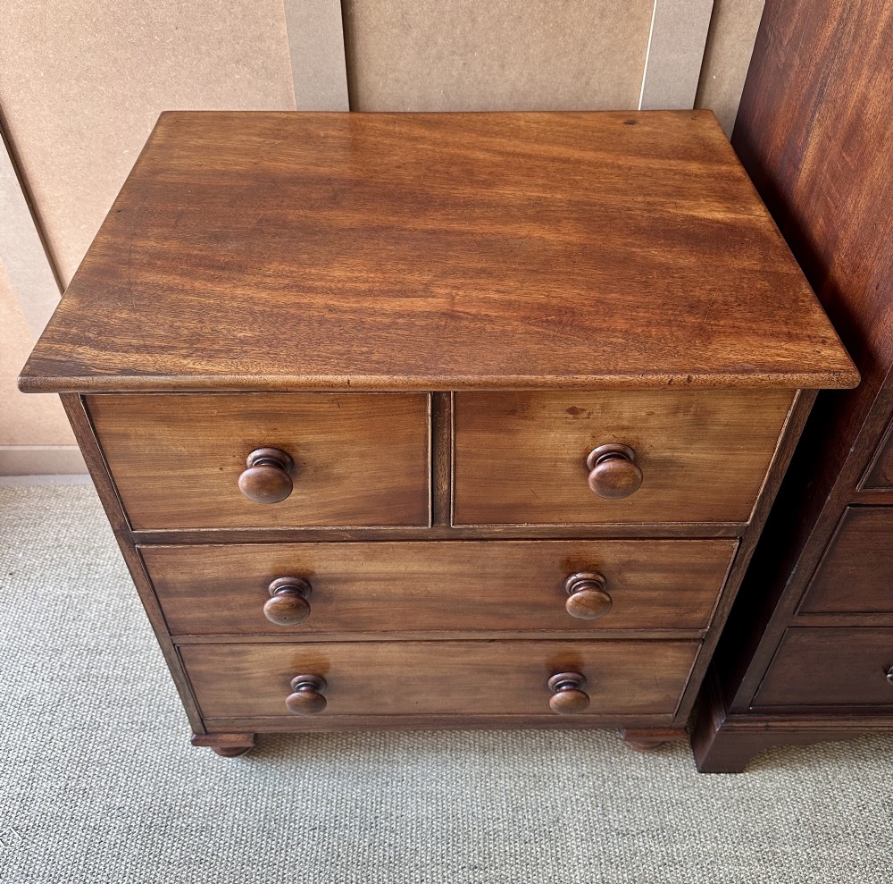 A small antique warm brown wood chest of drawers featuring two short drawers over two long drawers with turned wooden knobs and feet. View II
