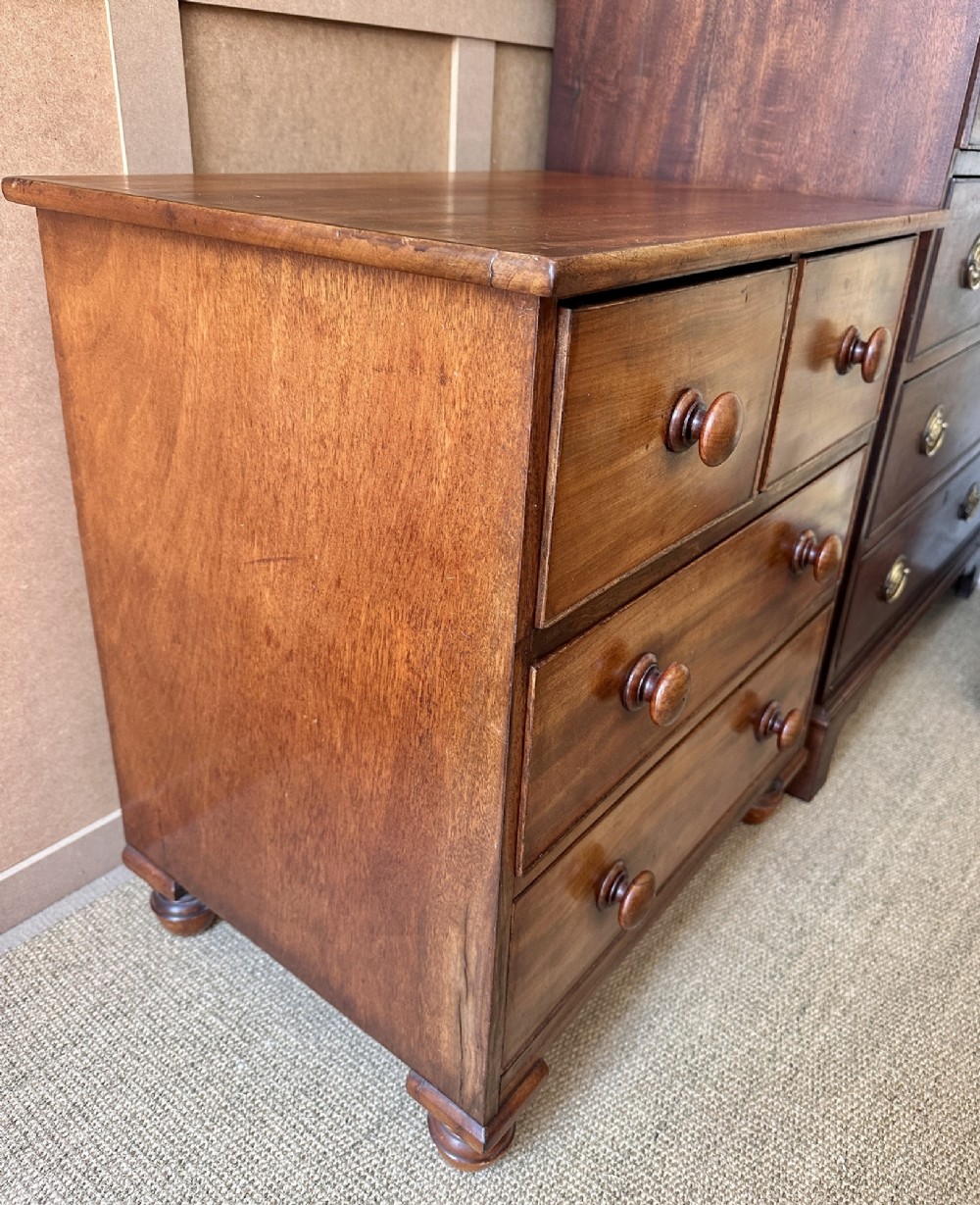 A small antique warm brown wood chest of drawers featuring two short drawers over two long drawers with turned wooden knobs and feet. View III