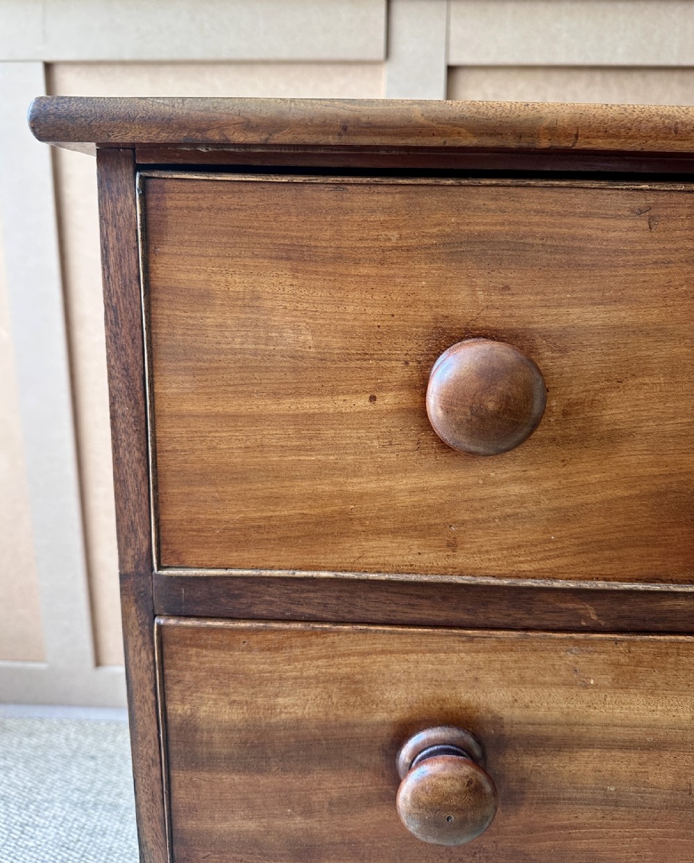 A small antique warm brown wood chest of drawers featuring two short drawers over two long drawers with turned wooden knobs and feet. View IV
