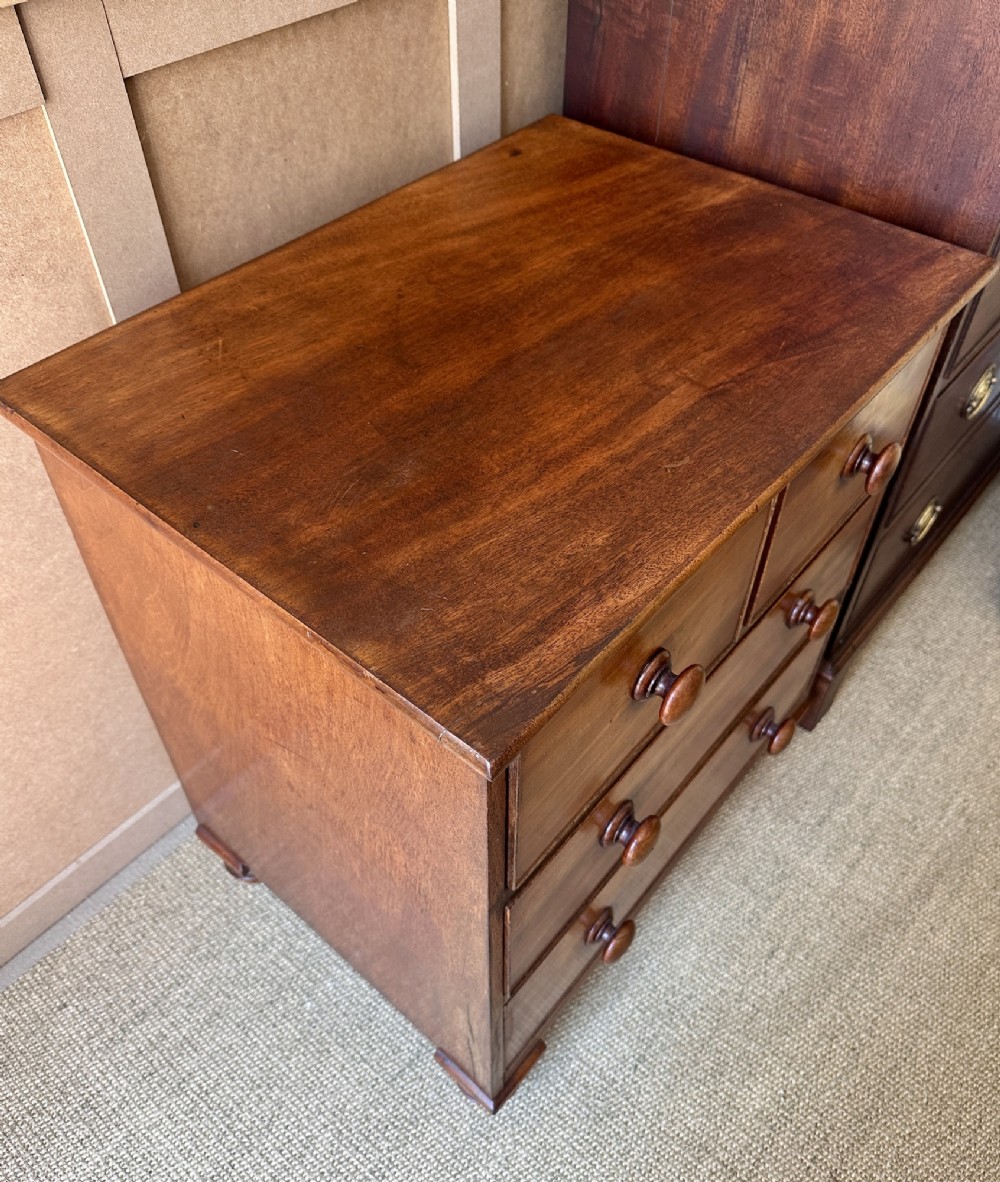 A small antique warm brown wood chest of drawers featuring two short drawers over two long drawers with turned wooden knobs and feet. View VI