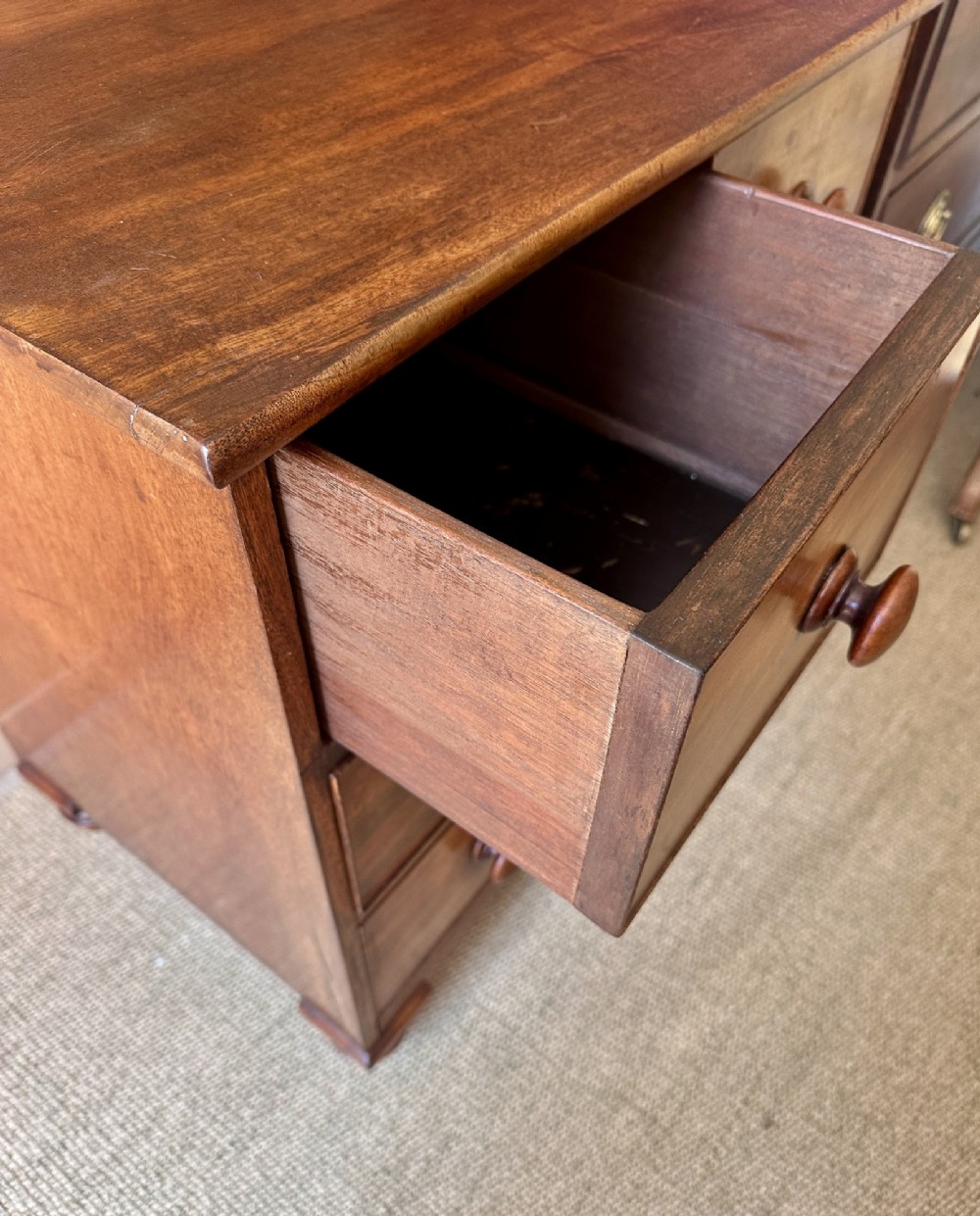 A small antique warm brown wood chest of drawers featuring two short drawers over two long drawers with turned wooden knobs and feet. View VII