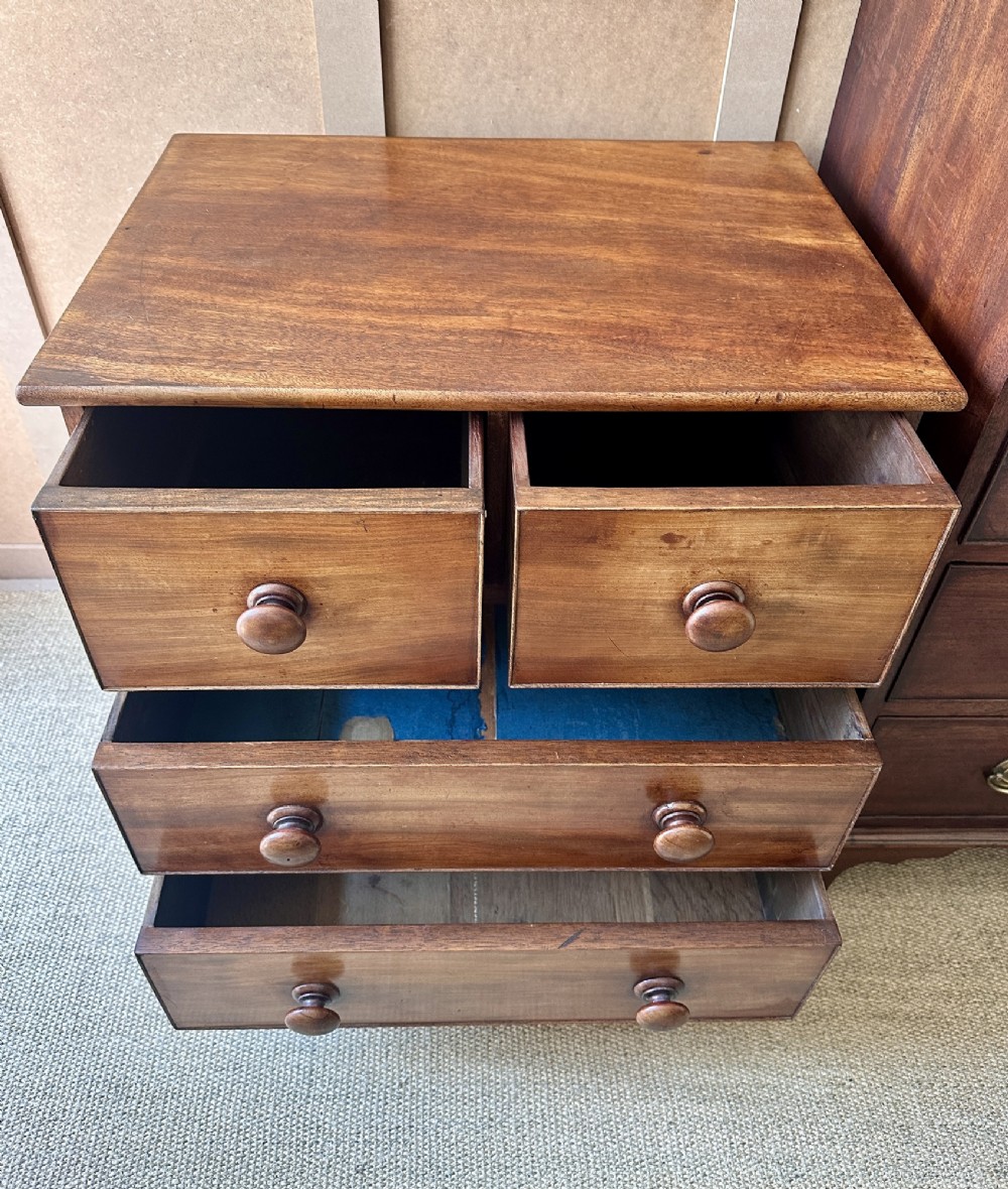 A small antique warm brown wood chest of drawers featuring two short drawers over two long drawers with turned wooden knobs and feet. View VIII