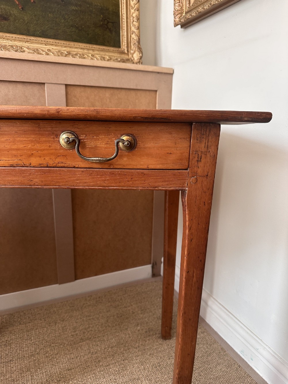 An antique pine side table featuring a single wide drawer with two brass bail handles, an overhanging rectangular top, and four square tapered legs. View III
