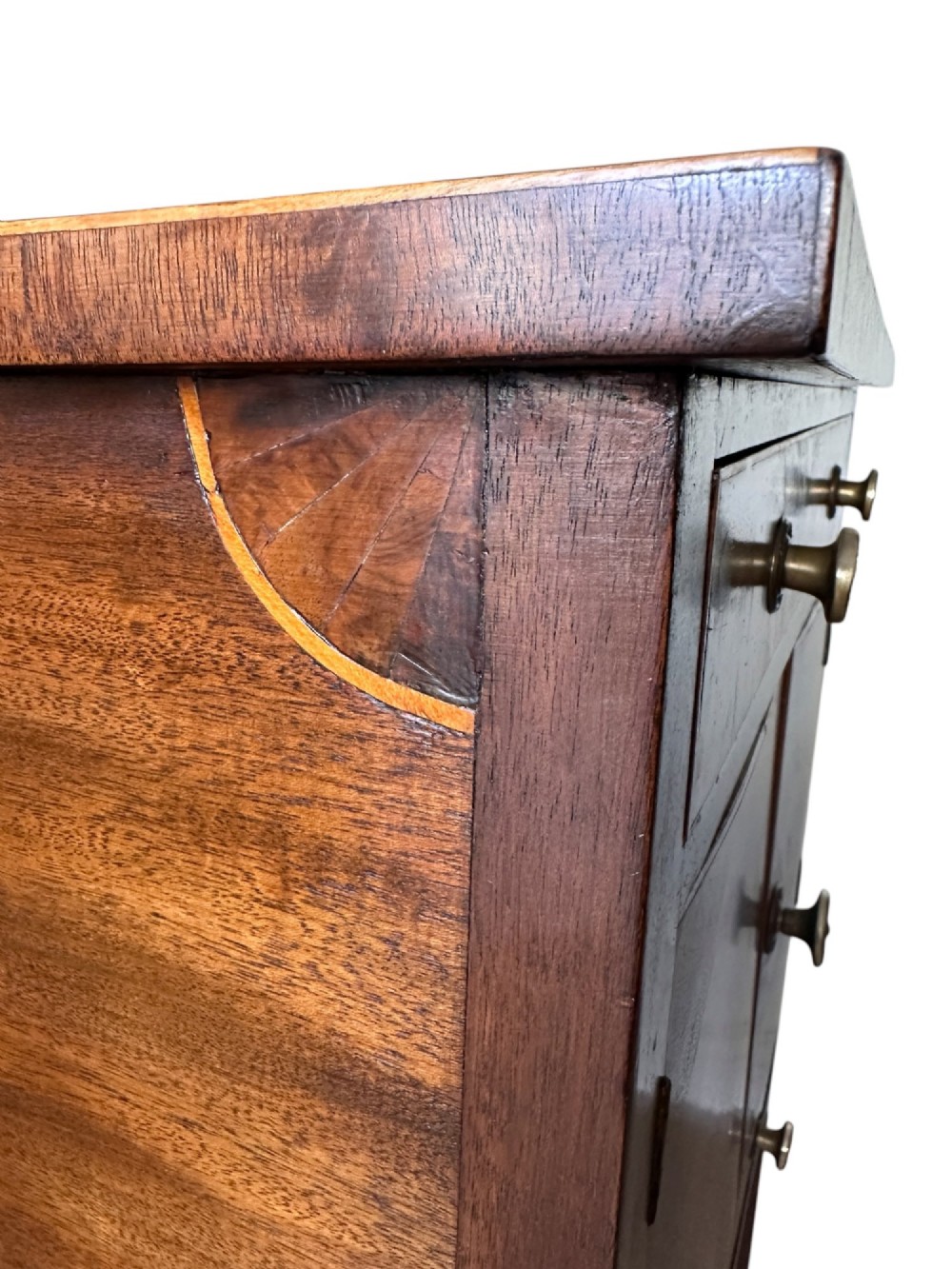 A Georgian flame mahogany bedside cabinet featuring a top drawer, central double doors, and a bottom drawer, supported by square tapered legs. View VI