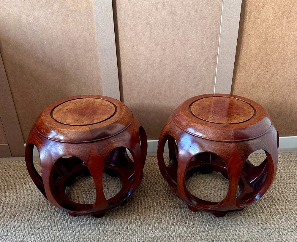 A pair of carved dark hardwood barrel stools featuring rounded openwork frames and circular burr wood inset tops. View II