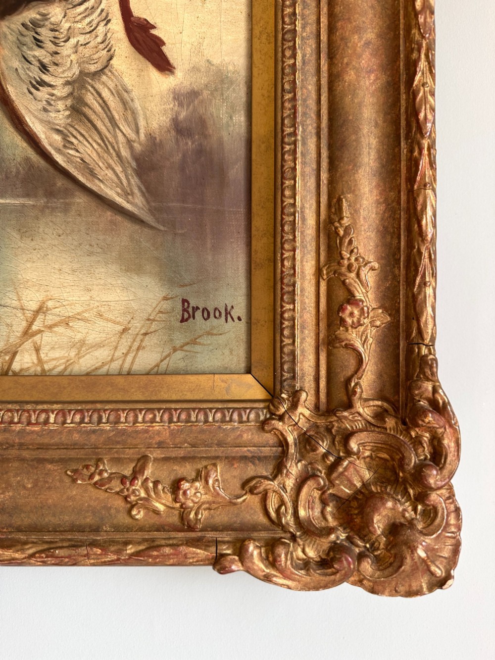 An early 20th-century oil painting depicting a brown and white gundog holding a mallard drake in its mouth, presented within an ornate gilt frame. View IV