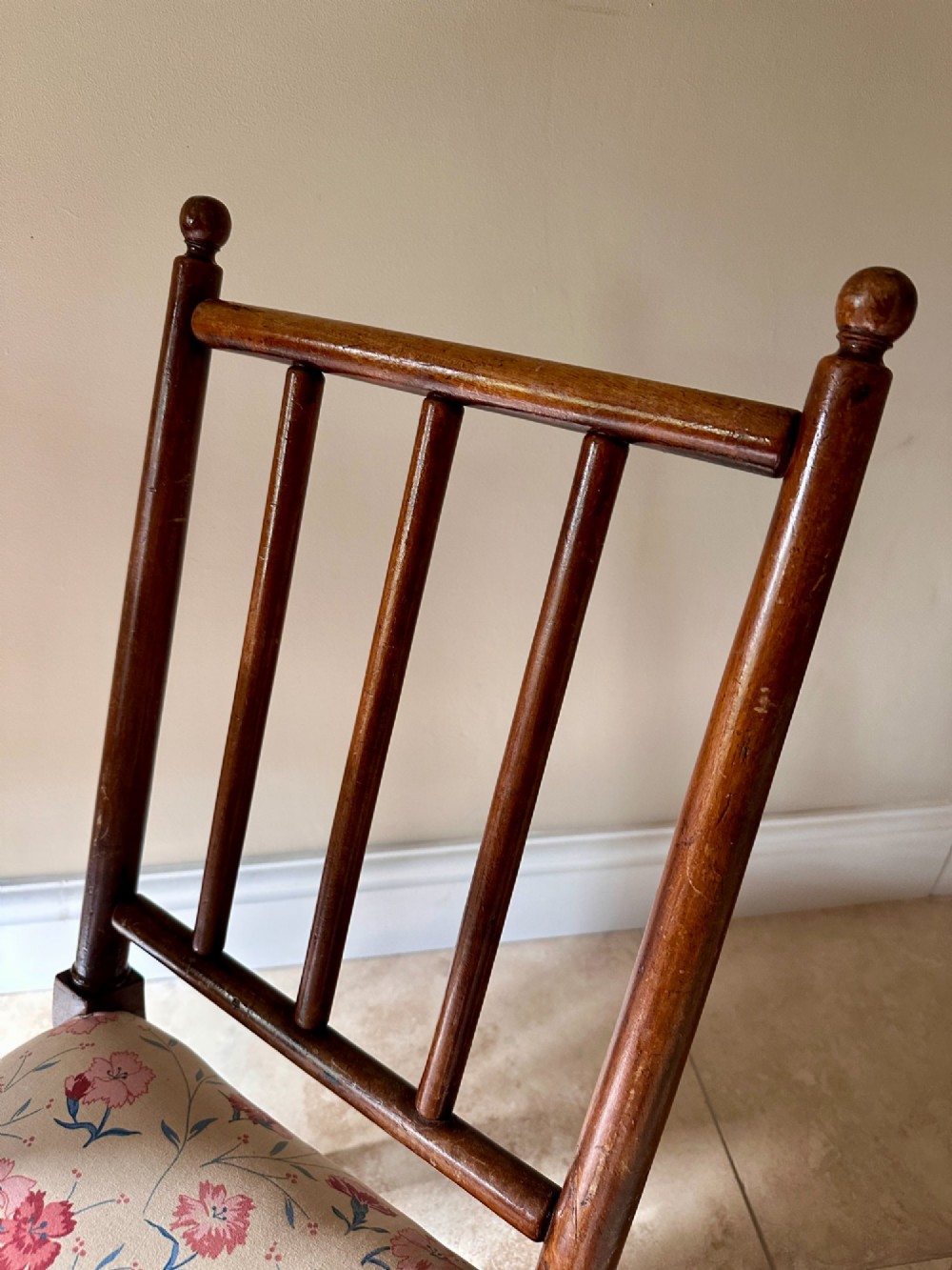 A low Victorian slipper chair featuring turned timber front legs on brass castors, a spindle back, and floral pattern textile upholstery. View II
