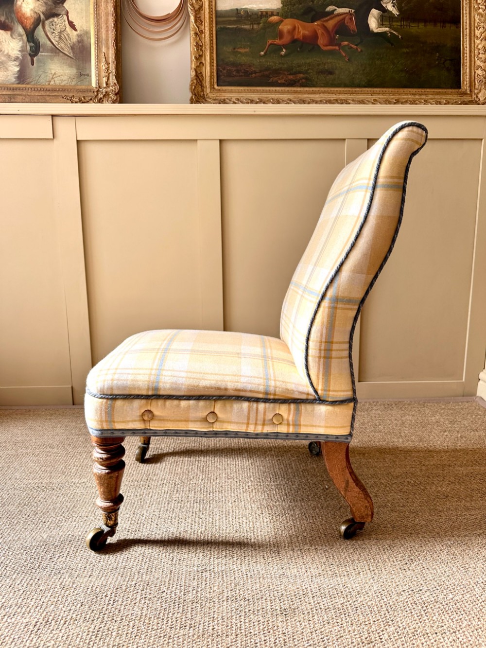 A low-seated Victorian armless slipper chair upholstered in yellow and cream tartan fabric with turned mahogany front legs on brass castors. View IV