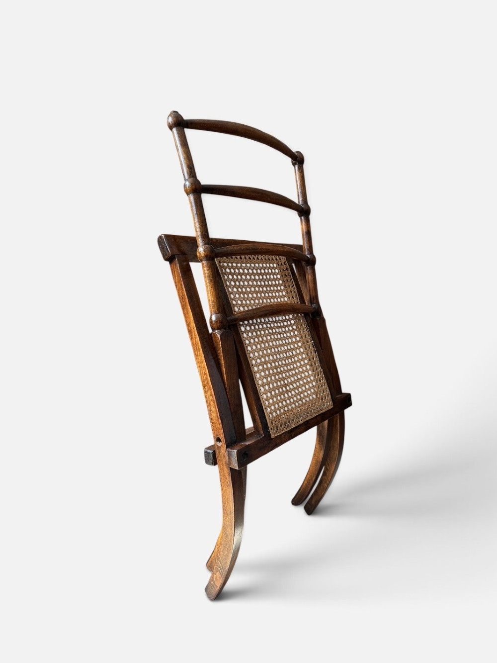 A nineteenth-century Aesthetic Movement folding campaign chair made from warm brown wood with a ladder back and woven cane seat. View IV