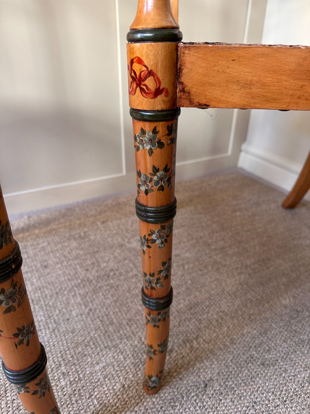 A pair of Edwardian Sheraton Revival painted wooden elbow chairs featuring woven cane seats, lattice backrests, and floral painted decoration. View VII